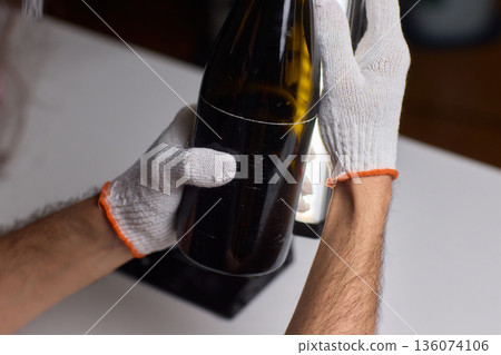 Creative craftsman meticulously cutting glass bottle in workshop setting, Experienced artisan safely transforming recycled bottle into new glassware with precision 136074106