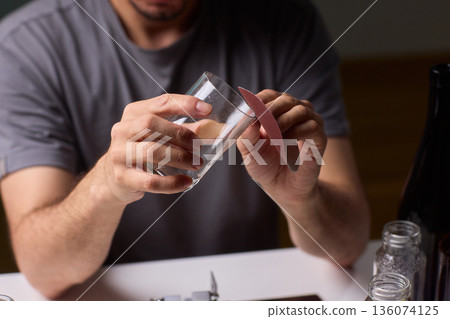Hands examine glass, Workshop scene showing person inspecting glass before finishing touches, Individual assesses edge of cut glass while preparing for polishing process Hands examine glass, Workshop scene showing person inspecting glass before finishing touches, Individual assesses edge of cut glass while preparing for polishing process 136074125