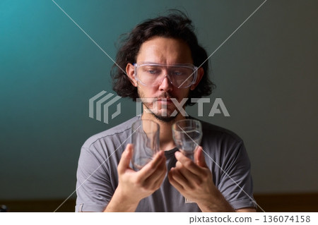 Hands examine glass, Workshop scene showing person inspecting glass before finishing touches, Individual assesses edge of cut glass while preparing for polishing process 136074158