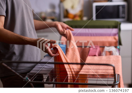 Housekeeper hangs pink towel in bathroom, Bright bathroom scene with towels drying after laundry, Indoor routine where housekeeper air dries linens on metal rack in sunlight 136074197