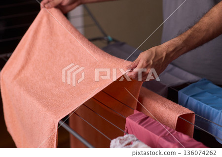 Housekeeper hangs pink towel in bathroom, Bright bathroom scene with towels drying after laundry, Indoor routine where housekeeper air dries linens on metal rack in sunlight 136074262