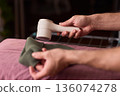 Close view of lint tool on wool, Man using lint roller to clean wool hat texture, Detailed scene of hand grooming fuzz from soft knitted wool hat with lint roller 136074278