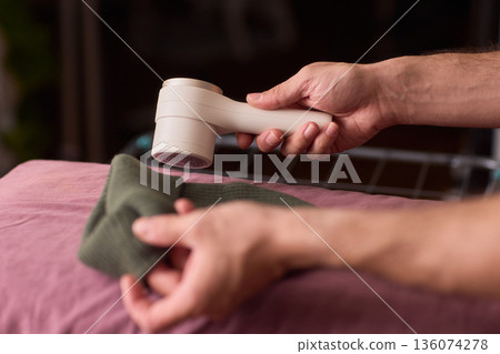 Close view of lint tool on wool, Man using lint roller to clean wool hat texture, Detailed scene of hand grooming fuzz from soft knitted wool hat with lint roller Close view of lint tool on wool, Man using lint roller to clean wool hat texture, Detailed scene of hand grooming fuzz from soft knitted wool hat with lint roller 136074278