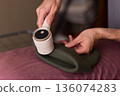 Close view of lint tool on wool, Man using lint roller to clean wool hat texture, Detailed scene of hand grooming fuzz from soft knitted wool hat with lint roller 136074283