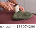Close view of lint tool on wool, Man using lint roller to clean wool hat texture, Detailed scene of hand grooming fuzz from soft knitted wool hat with lint roller 136074290
