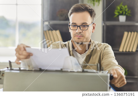 Focused writer editing page on vintage typewriter at modern home office workspace 136075191