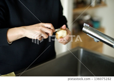 Peeling potatoes with a peeler Peeling potatoes with a peeler 136075282