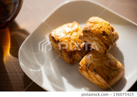 Scones and tea set on white plates illuminated by natural light from a window Scones and tea set on white plates illuminated by natural light from a window 136075425