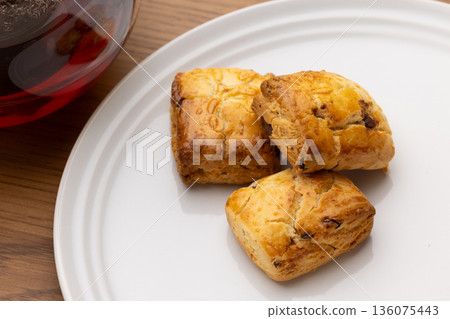 Scones and tea set on white plates illuminated by natural light from a window Scones and tea set on white plates illuminated by natural light from a window 136075443