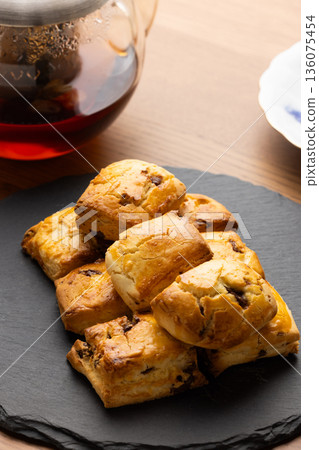 Scones and tea set on a black plate illuminated by natural light from the window Scones and tea set on a black plate illuminated by natural light from the window 136075454