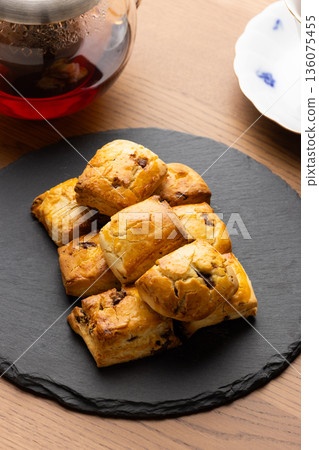 Scones and tea set on a black plate illuminated by natural light from the window Scones and tea set on a black plate illuminated by natural light from the window 136075455
