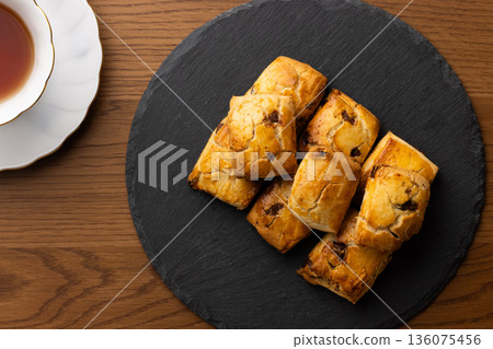 Scones and tea set on a black plate illuminated by natural light from the window Scones and tea set on a black plate illuminated by natural light from the window 136075456