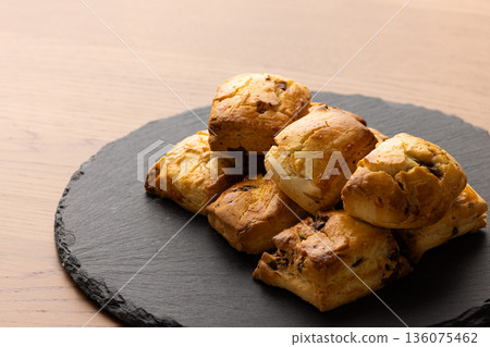 Scones on a black plate lit by natural light from a window 136075462