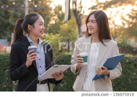 businesswomen team reviewing and discussing a business project outside office building. 136075819