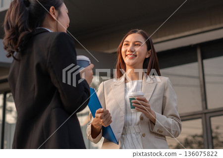 businesswomen team reviewing and discussing a business project outside office building. 136075822