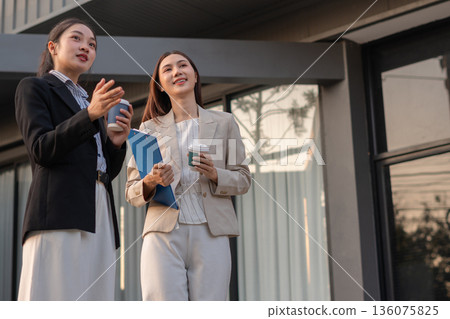 businesswomen team reviewing and discussing a business project outside office building. 136075825