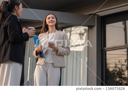 businesswomen team reviewing and discussing a business project outside office building. 136075826