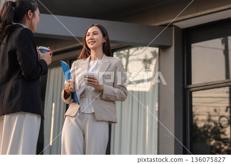 businesswomen team reviewing and discussing a business project outside office building. 136075827