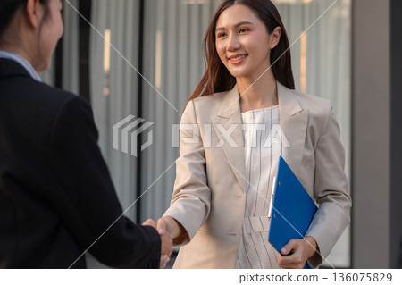 Business women shake hands after agreeing to start a new project successfully. 136075829