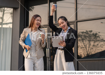 Excited businesswomen celebrating success, teamwork, and achievement in a modern office. Confidence, joy, and financial results inspire the perfect corporate moment. Excited businesswomen celebrating success, teamwork, and achievement in a modern office. Confidence, joy, and financial results inspire the perfect corporate moment. 136075835