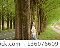 A smiling woman strolling along the Metasequoia tree-lined path in fresh greenery 136076609
