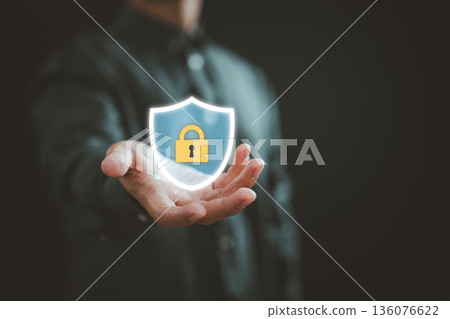 Businessman holding glowing shield with lock icon representing digital security and data protection 136076622