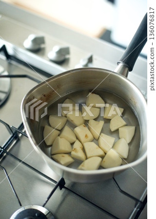Cut potatoes being boiled in a pot 136076817