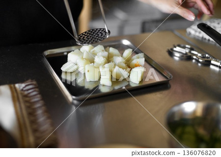 Mashing boiled potatoes with a masher 136076820