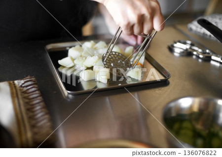 Mashing boiled potatoes with a masher 136076822