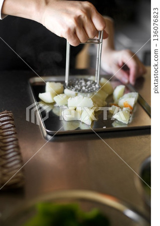 Mashing boiled potatoes with a masher 136076823