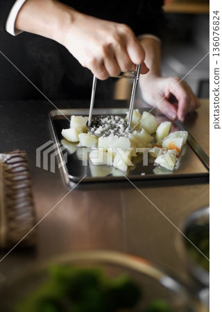 Mashing boiled potatoes with a masher Mashing boiled potatoes with a masher 136076824