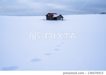 雪地上的腳印和一間孤零零的小屋,訴說著一幅靜謐冬日景象的故事。 雪地上的腳印和一間孤零零的小屋,訴說著一幅靜謐冬日景象的故事。 136076915