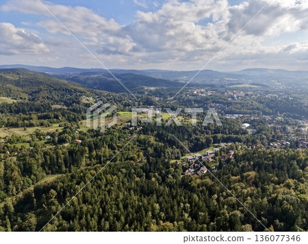 Scene Depicting Natural Greenery Transitioning Into Urban Development Beneath Layered Cloud Formations 136077346
