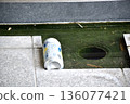 Discarded aluminum cans floating in the water of a street drain 136077421