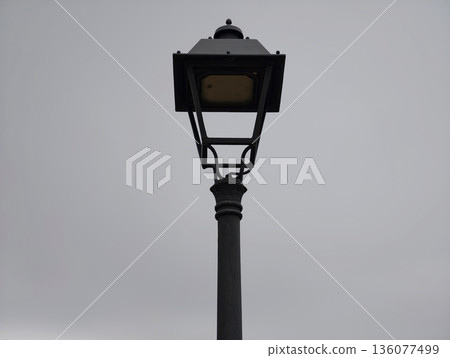 Desolate lamp silhouette, Lone street lamp stands against heavy overcast sky in tranquil cityscape 136077499