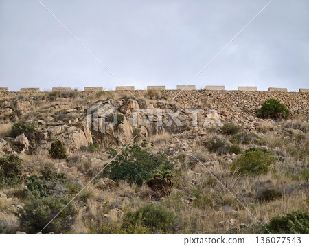 Old fortified stone boundary marks barren landscape with sparse vegetation and rocky formations Old fortified stone boundary marks barren landscape with sparse vegetation and rocky formations 136077543