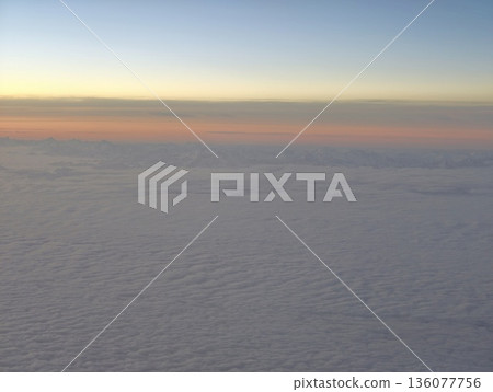 Serene dawn with soft cloudy horizon, Tranquil sunrise casting warm tones over expansive clouds 136077756