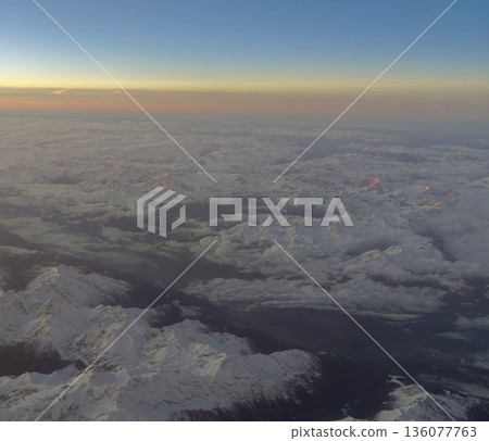 Tranquil snowcovered peaks under pastel sky with cloud layers and distant glacier textures Tranquil snowcovered peaks under pastel sky with cloud layers and distant glacier textures 136077763