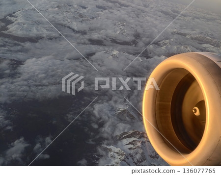 Highaltitude view of jet with illuminated turbine face above snowy terrain and distant horizon Highaltitude view of jet with illuminated turbine face above snowy terrain and distant horizon 136077765