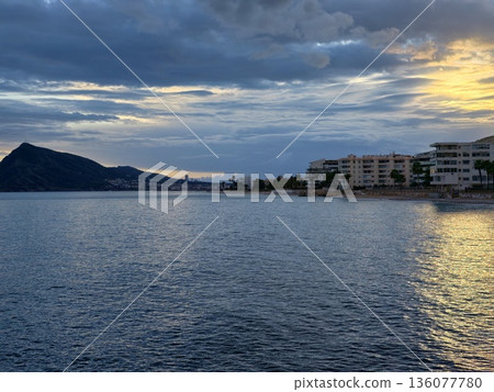 Tranquil waters with mountain silhouette, Peaceful seascape featuring distant hills and clouds 136077780