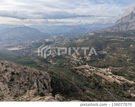 Aerial shot of rugged landscape, Drone imagery reveals mountain pass with scattered dwellings nearby 136077870