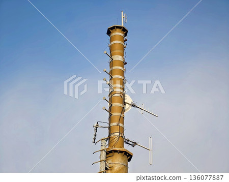 Old factory smokestack, Weathered industrial pipe with corroded ladder and atmospheric background Old factory smokestack, Weathered industrial pipe with corroded ladder and atmospheric background 136077887