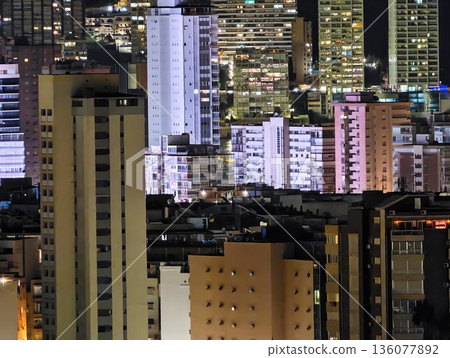 Vivid city skyline illuminated with glowing structures and energetic nighttime urban atmosphere Vivid city skyline illuminated with glowing structures and energetic nighttime urban atmosphere 136077892