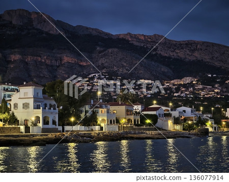 Luxurious seaside villa glowing brightly at dusk with managed outdoor lighting and guest access points 136077914
