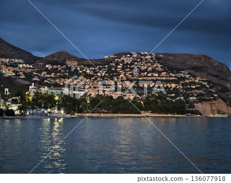 Resort during dusk featuring bright residences and descending lanes with staff coordinating guest arrivals 136077918