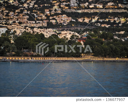 Peaceful waters with glowing homes, Gentle ripples dance across tranquil water under starry sky Peaceful waters with glowing homes, Gentle ripples dance across tranquil water under starry sky 136077937