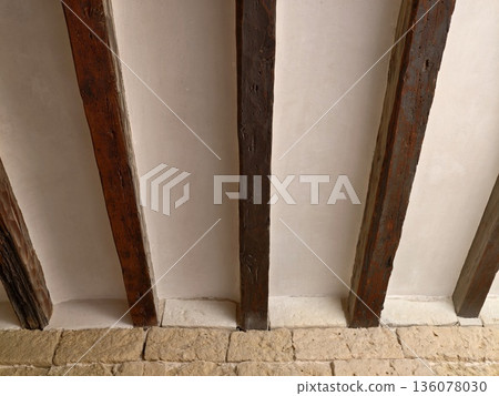 Restoration scene showing carpenter examining aged timber and stonework with warm sunlight 136078030