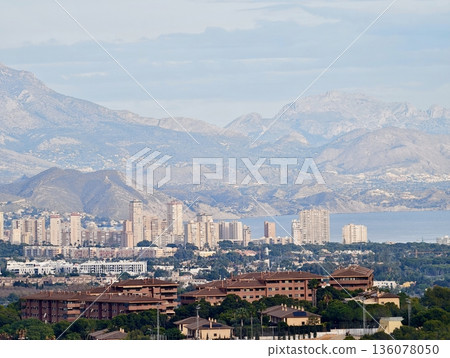 Cityscape against mountains, City skyline outlined by rugged mountain chains and layered ridgelines Cityscape against mountains, City skyline outlined by rugged mountain chains and layered ridgelines 136078050