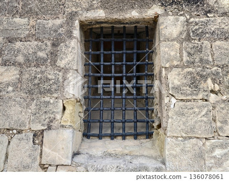 Weathered stone with iron bars, Scene depicting aged stone wall with fortified iron barred window 136078061