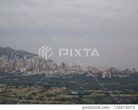 Coastal urban area observable from farmland with gentle fog shrouding structures throughout region 136078078